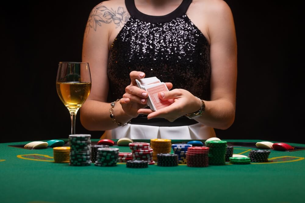 Girl dealer or croupier shuffles poker cards in a casino on the background of a table, chips, .Concept of poker game, game business, nightlife
