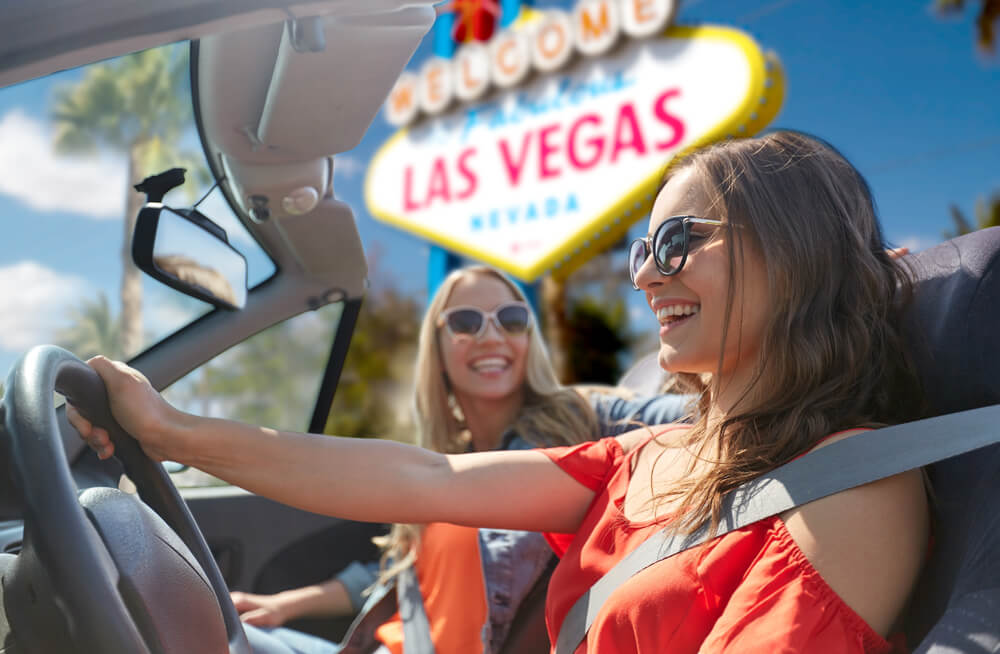 two women driving by the las vegas sign